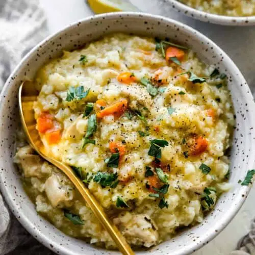 chicken and rice soup with fresh parsley on top and a gold spoon inside the bowl