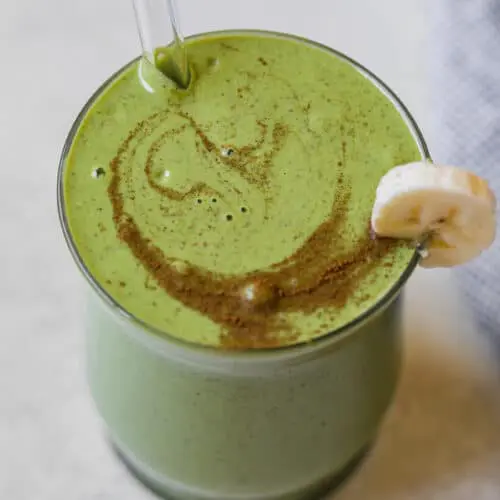 banana spinach smoothie in a cup with a glass straw