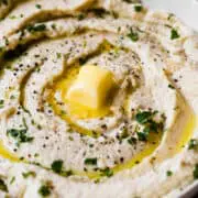 prepared mashed cauliflower in a serving bowl with a glob of butter on top