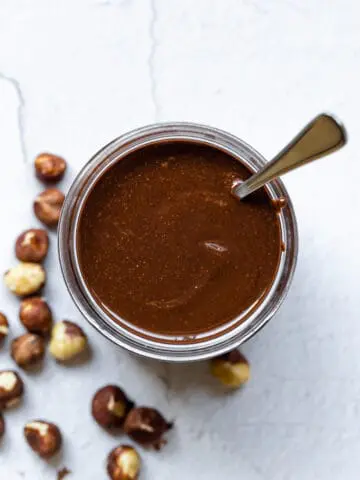 Nutella in a glass jar with a spoon inside
