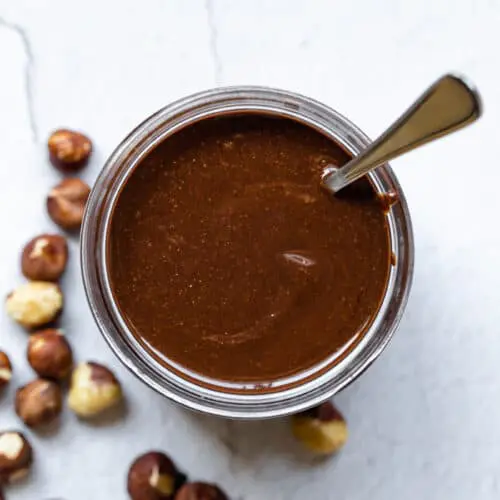 Nutella in a glass jar with a spoon inside