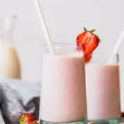 strawberry banana smoothie in a glass cup with a straw