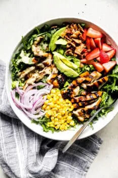 honey mustard chicken salad with avocado, onions, and corn in a large bowl