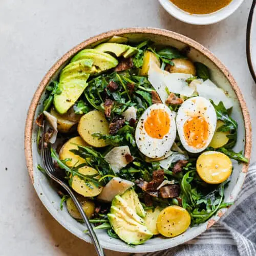 salad with eggs, avocado, potatoes, and bacon on a plate