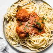 turkey meatballs on a plate with bucatini pasta and a fork