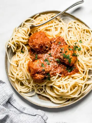 turkey meatballs on a plate with bucatini pasta and a fork