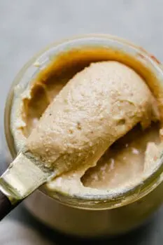 cashew butter being scooped out of a jar