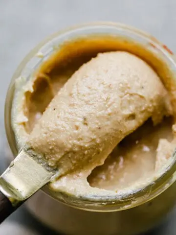 cashew butter being scooped out of a jar