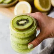 holding a kiwi cocktail with a fresh kiwi slice on top