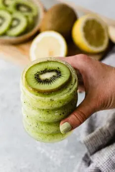 holding a kiwi cocktail with a fresh kiwi slice on top