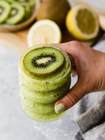 holding a kiwi cocktail with a fresh kiwi slice on top