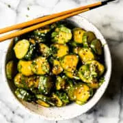 Korean cucumber salad in a ceramic bowl with sesame seeds and wooden chopsticks