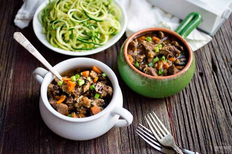 Korean Beef Soup in small white and green pots next to zucchini noodles with two forks