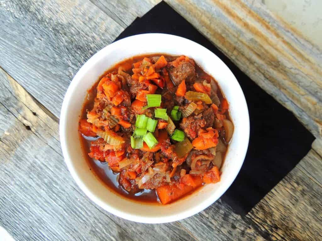 Hearty Buffalo Stew in a white bowl with sliced green onion