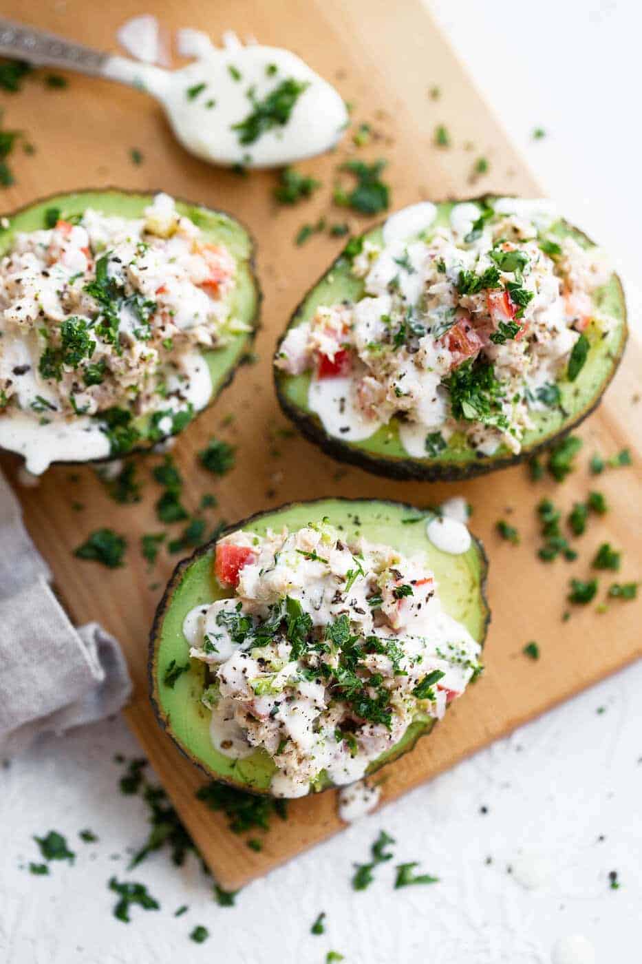Avocados filled with tuna salad on a wooden chopping board