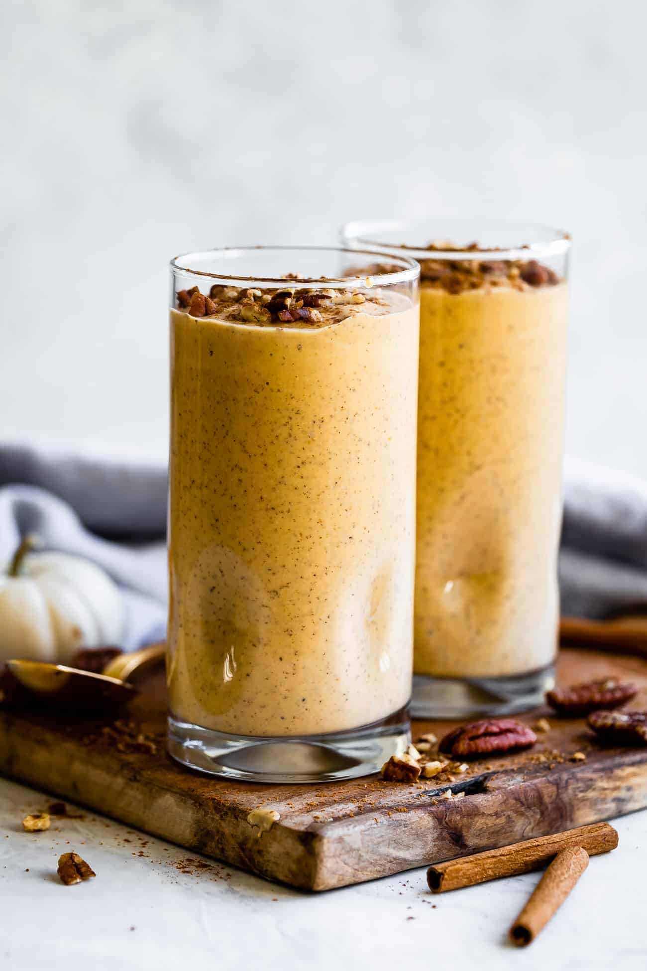 two pumpkin smoothies in glass cups with crushed pecans on top