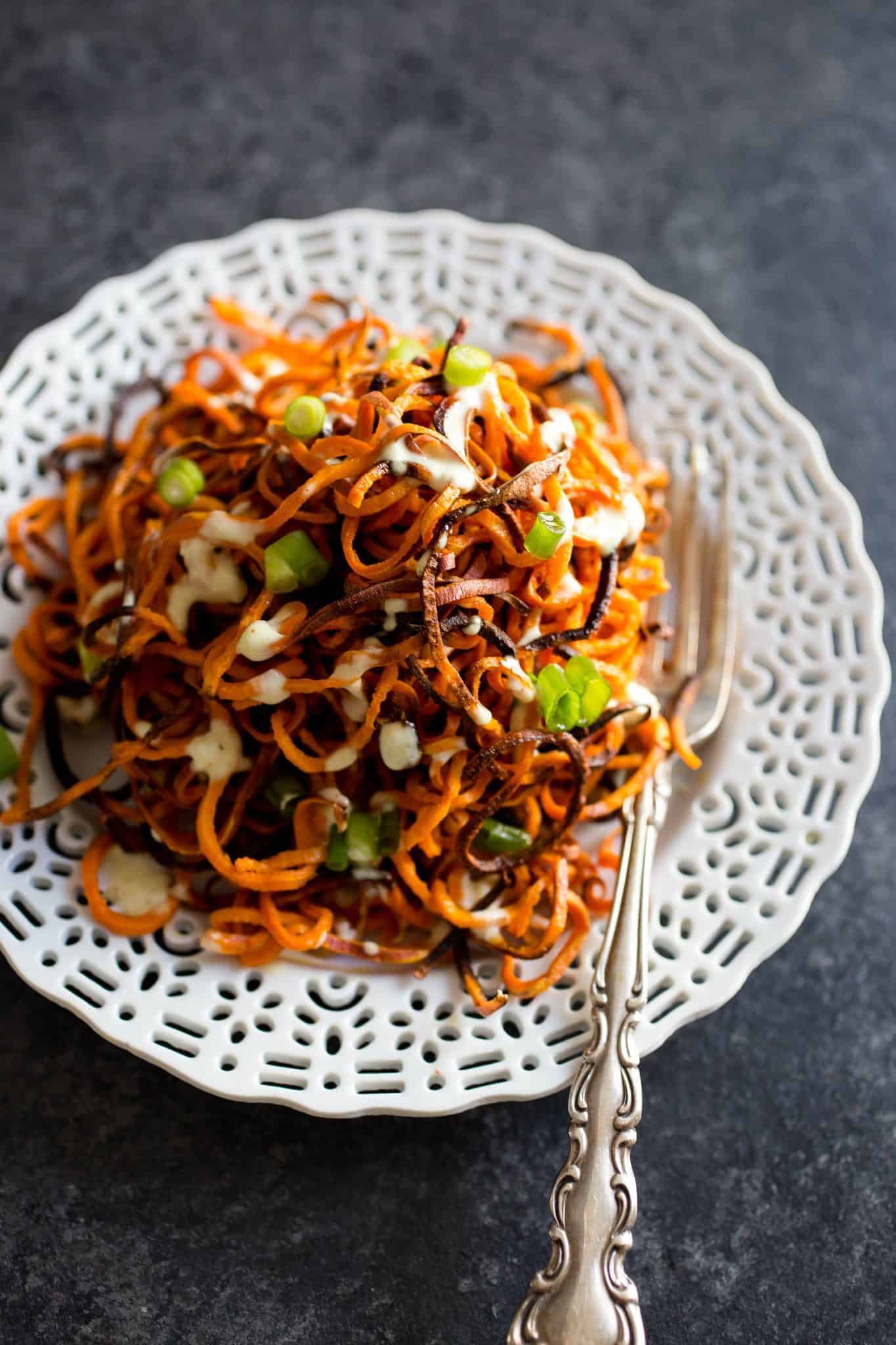Spiralized Sweet Potato Fries on a plate with a fork and green onions