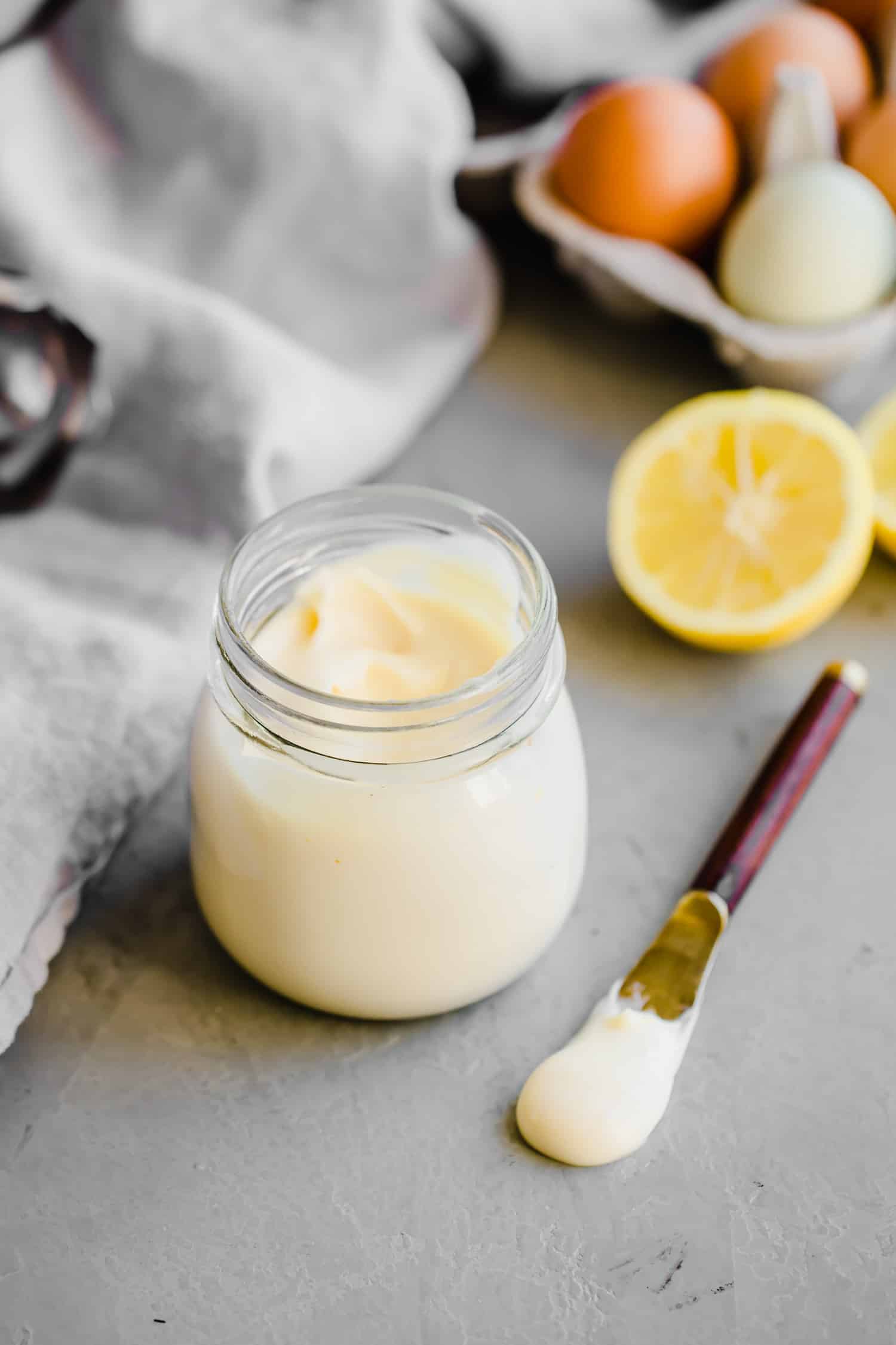 a jar of paleo mayo with a lemon on the side and a spoonful next to it