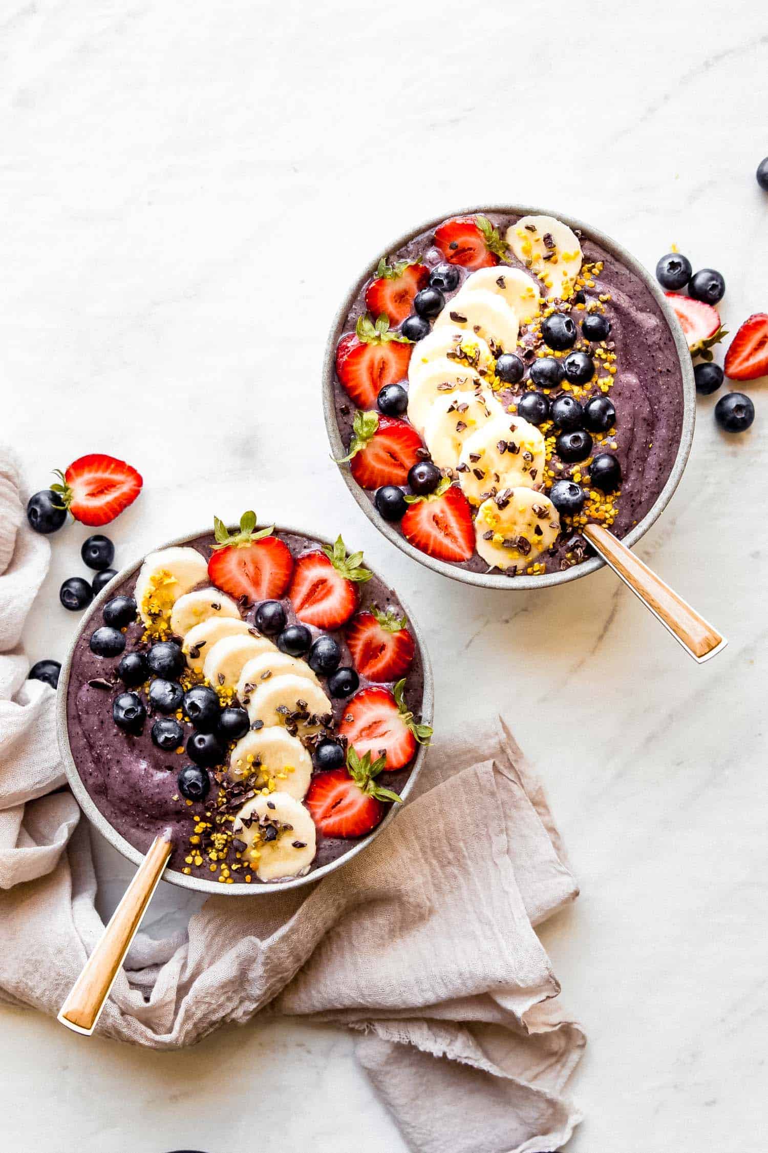 acai bowls with toppings, spoons on the side and a linen napkin