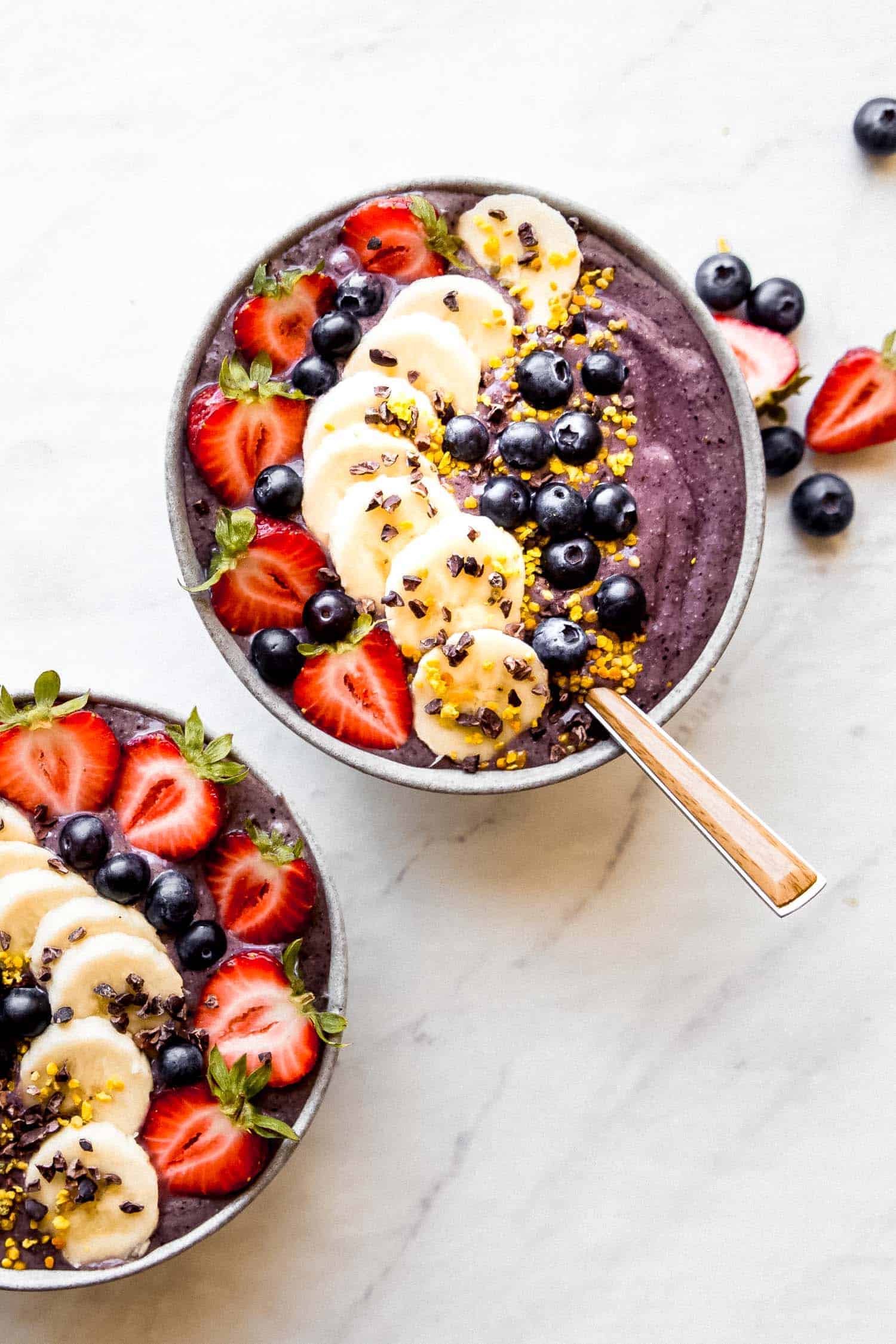 a vegan acai bowl with strawberries, blueberries and bananas on top