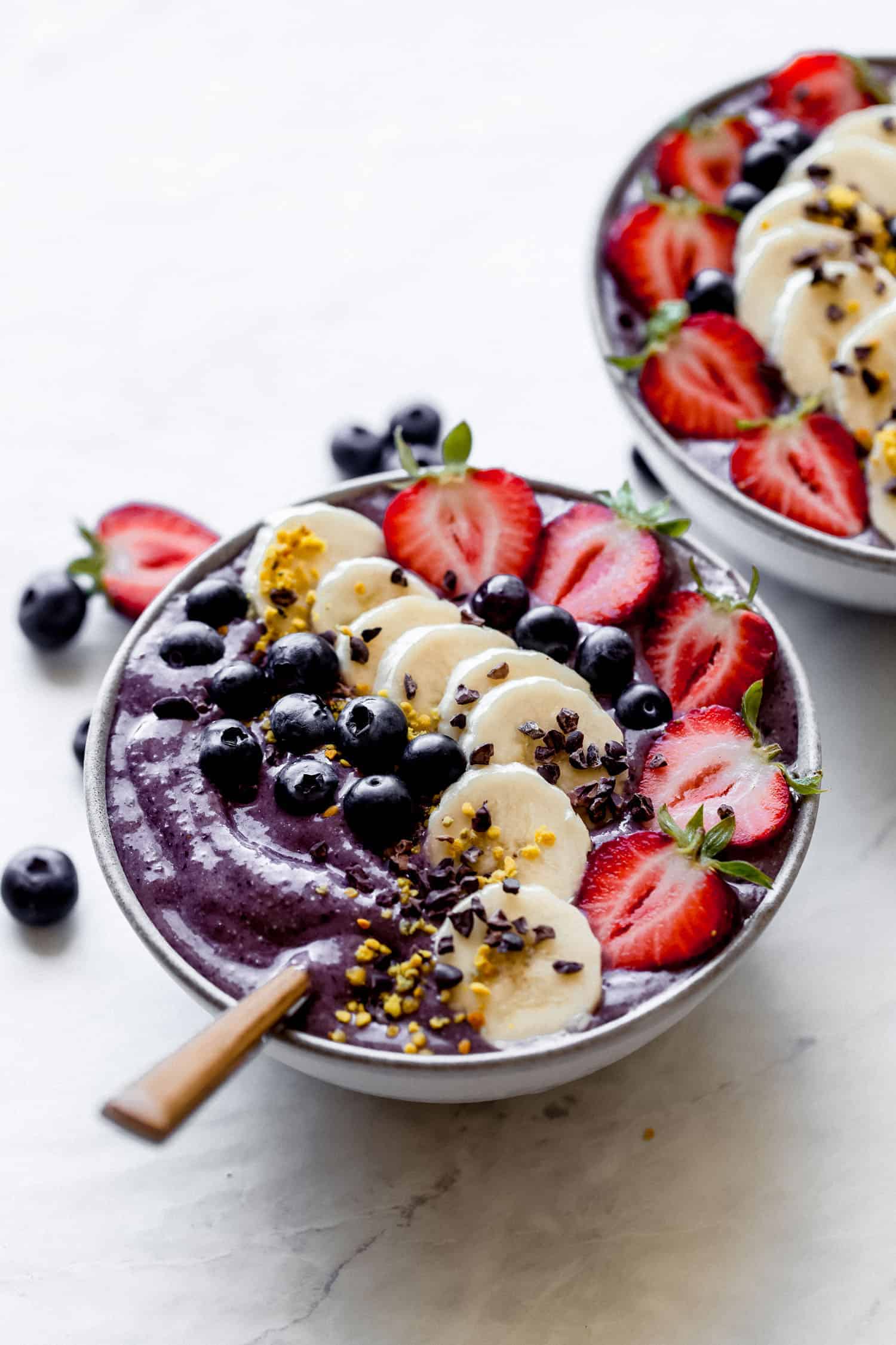 vegan acai bowl topped off with berries and bananas and a spoon