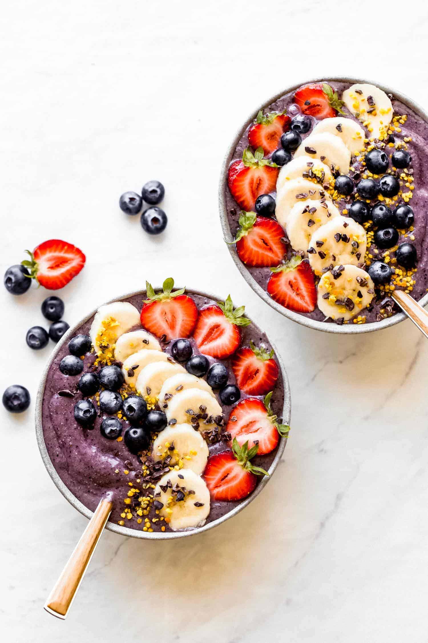 two acai bowls with berries and bananas on top