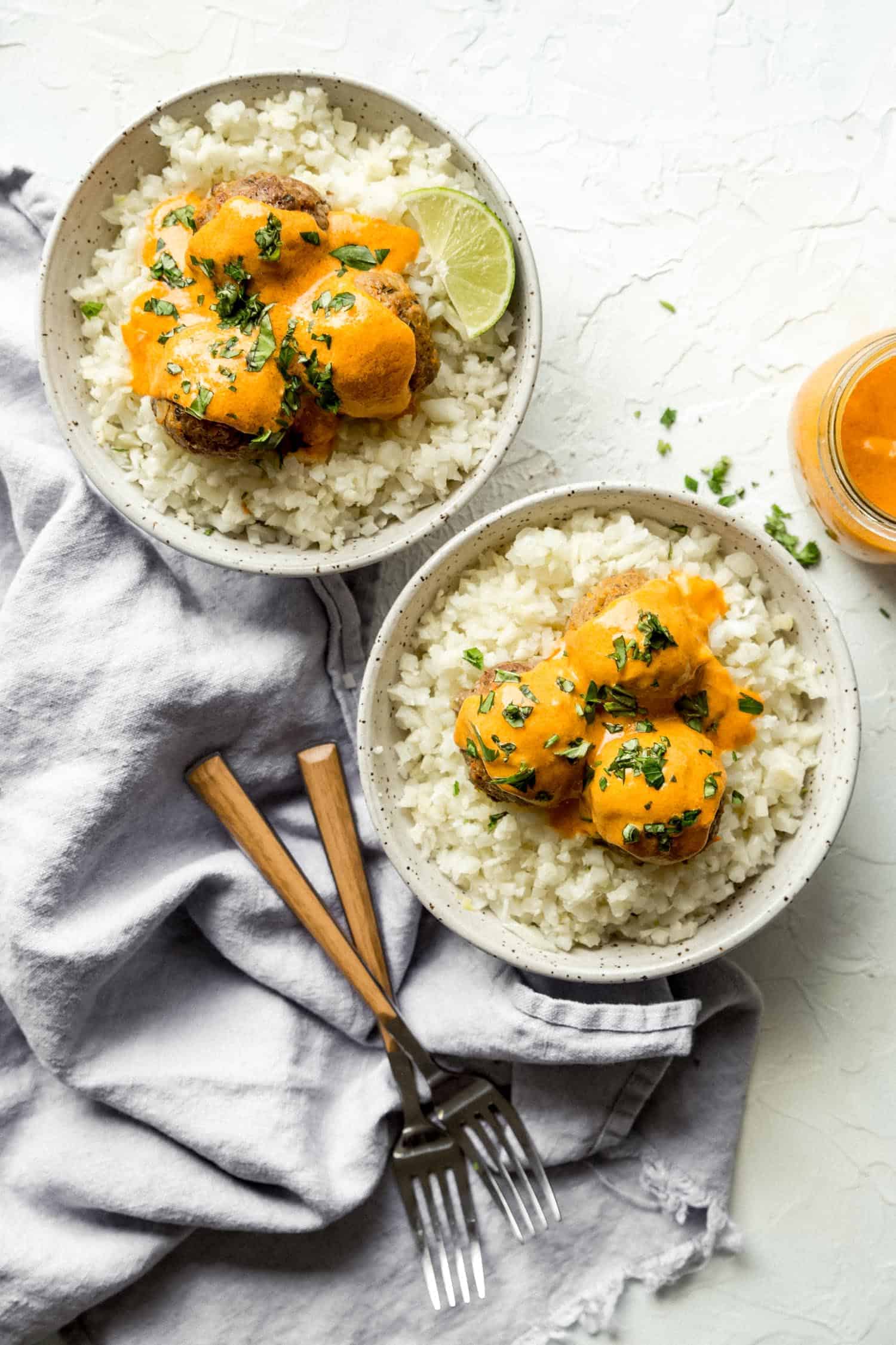 overhead of meatballs in two bowls with forks and curry sauce