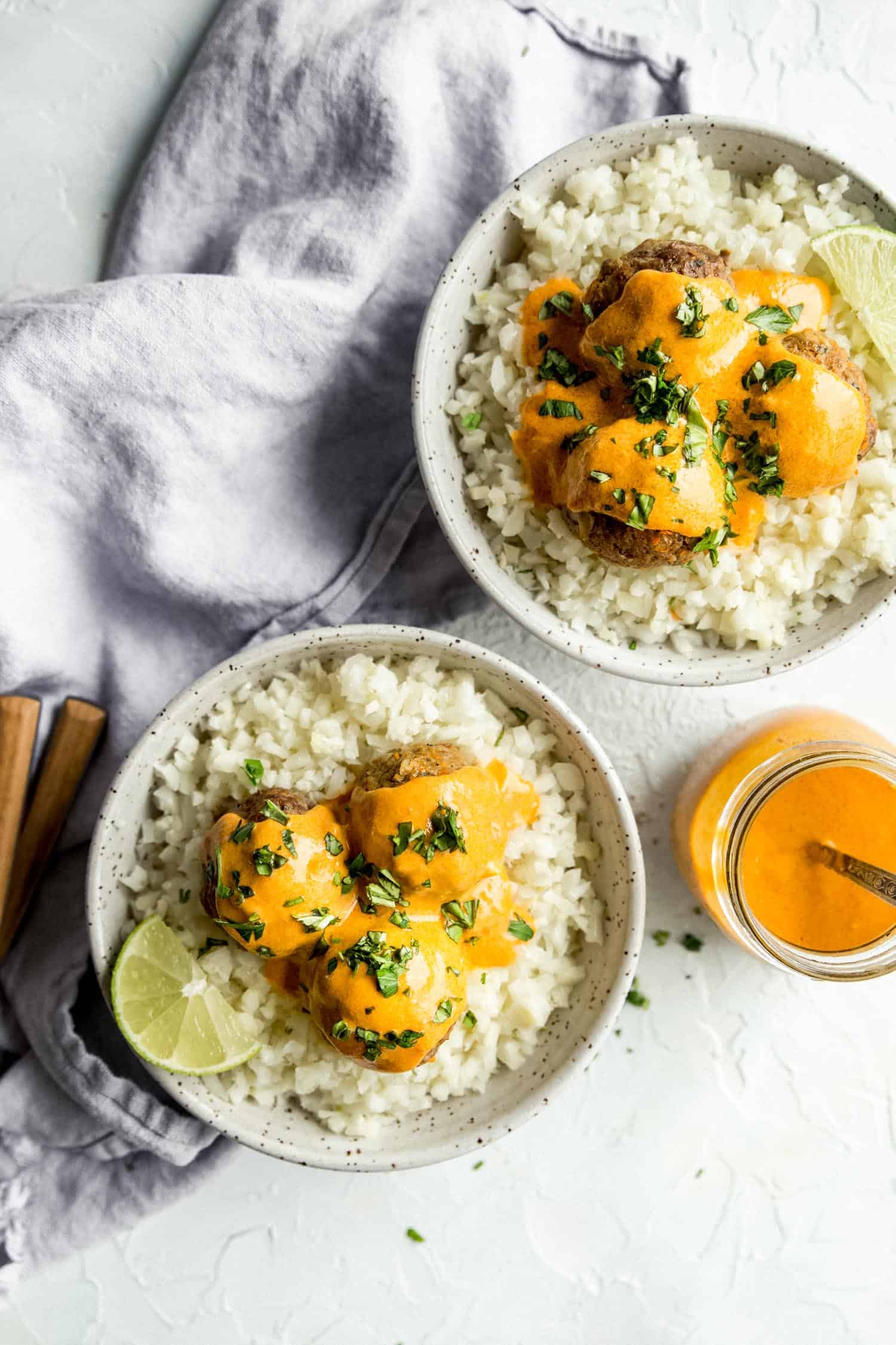 curry meatballs in two bowls with cauliflower rice
