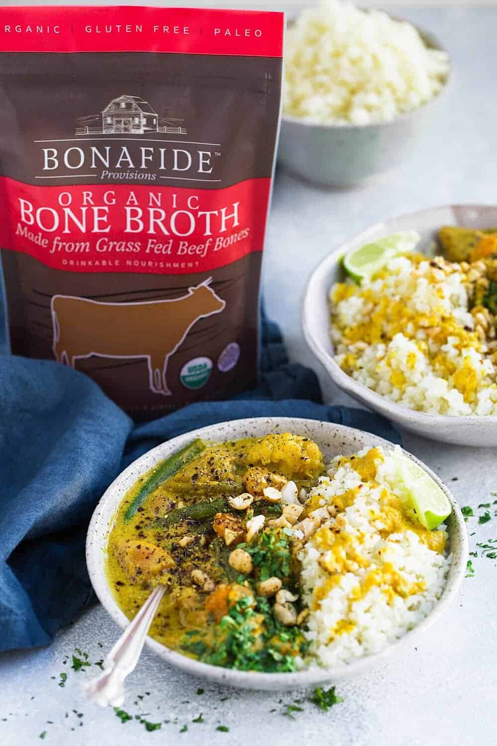 Chicken curry in a bowl next to a packet of bone broth