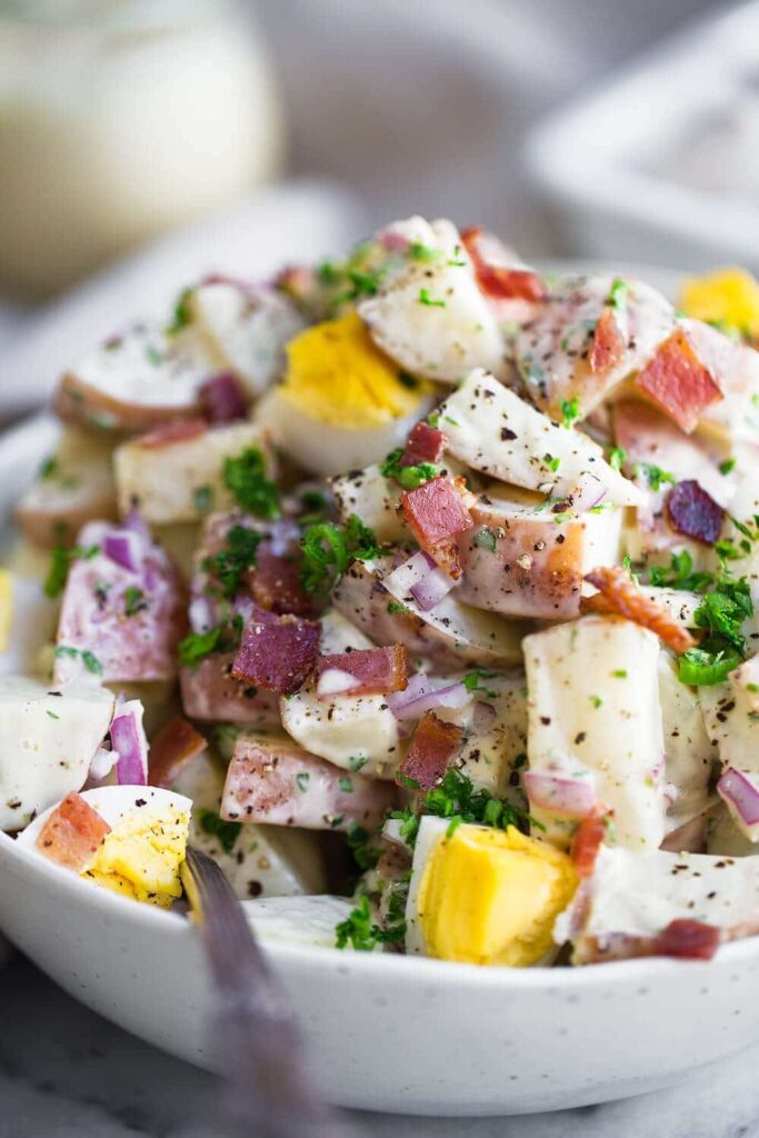 close up of whole30 potato salad in a bowl with crunchy bacon and eggs