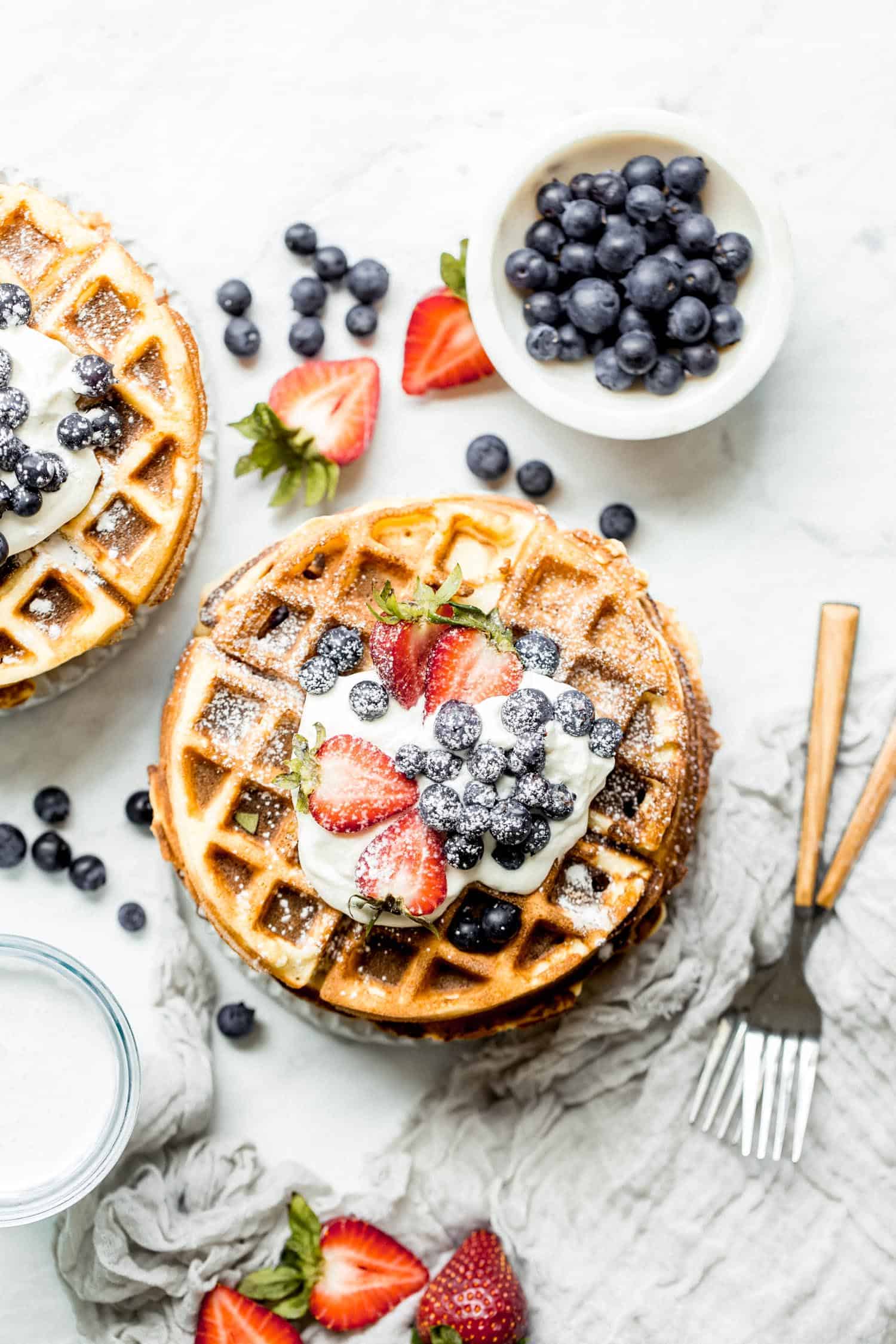 two stacks of paleo waffles on plates with berries