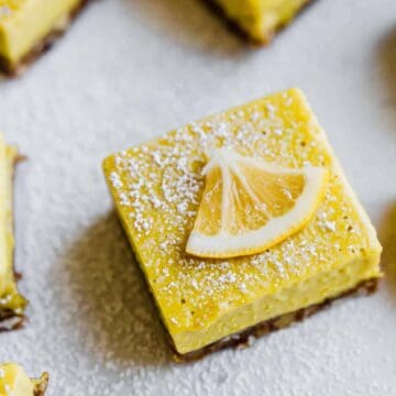 dairy free lemon bars on parchment paper with powdered sugar on top