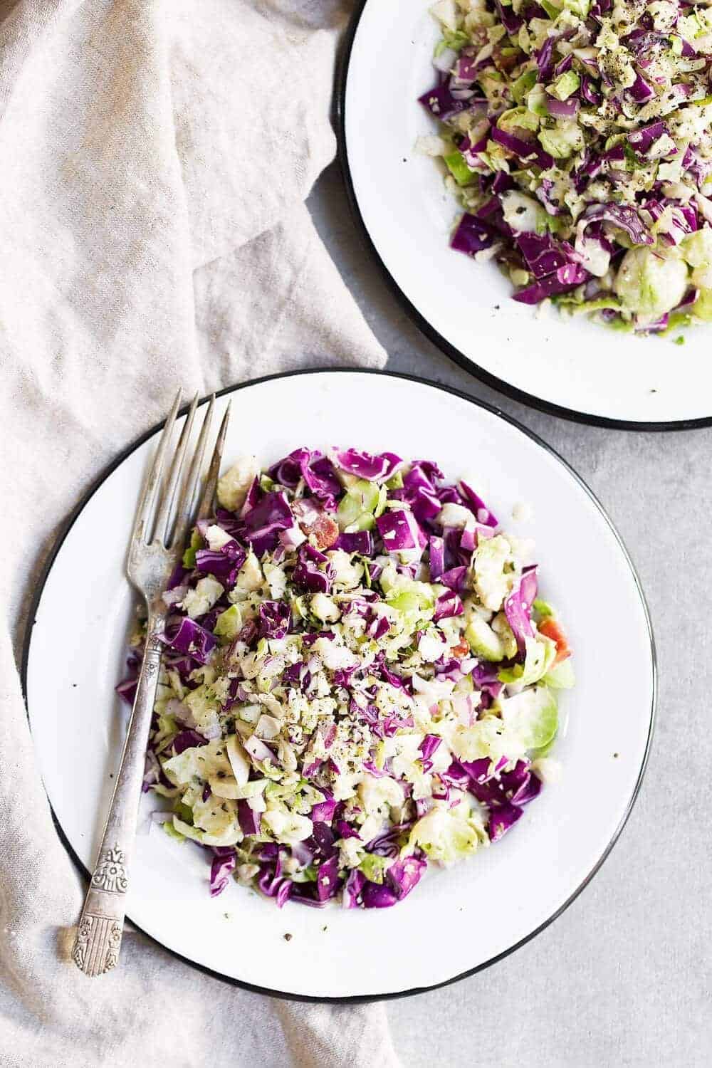 Two plates of Brussels Sprout Slaw with a fork