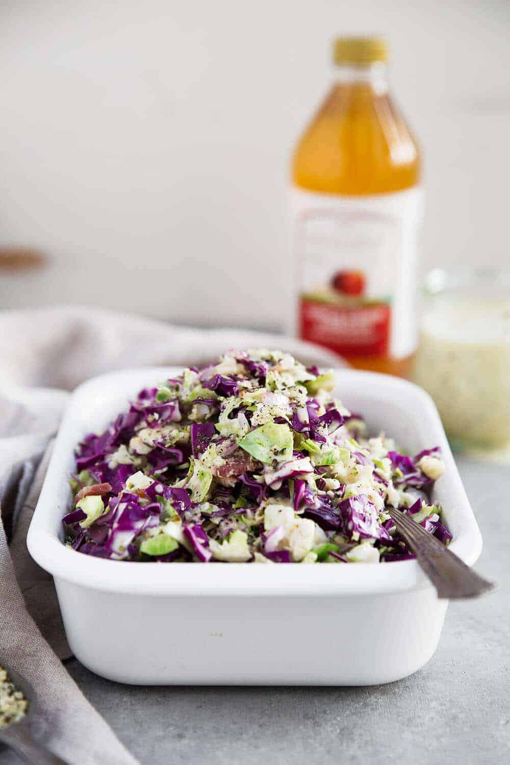 Brussels Sprout Slaw with apple cider vinegar in the background