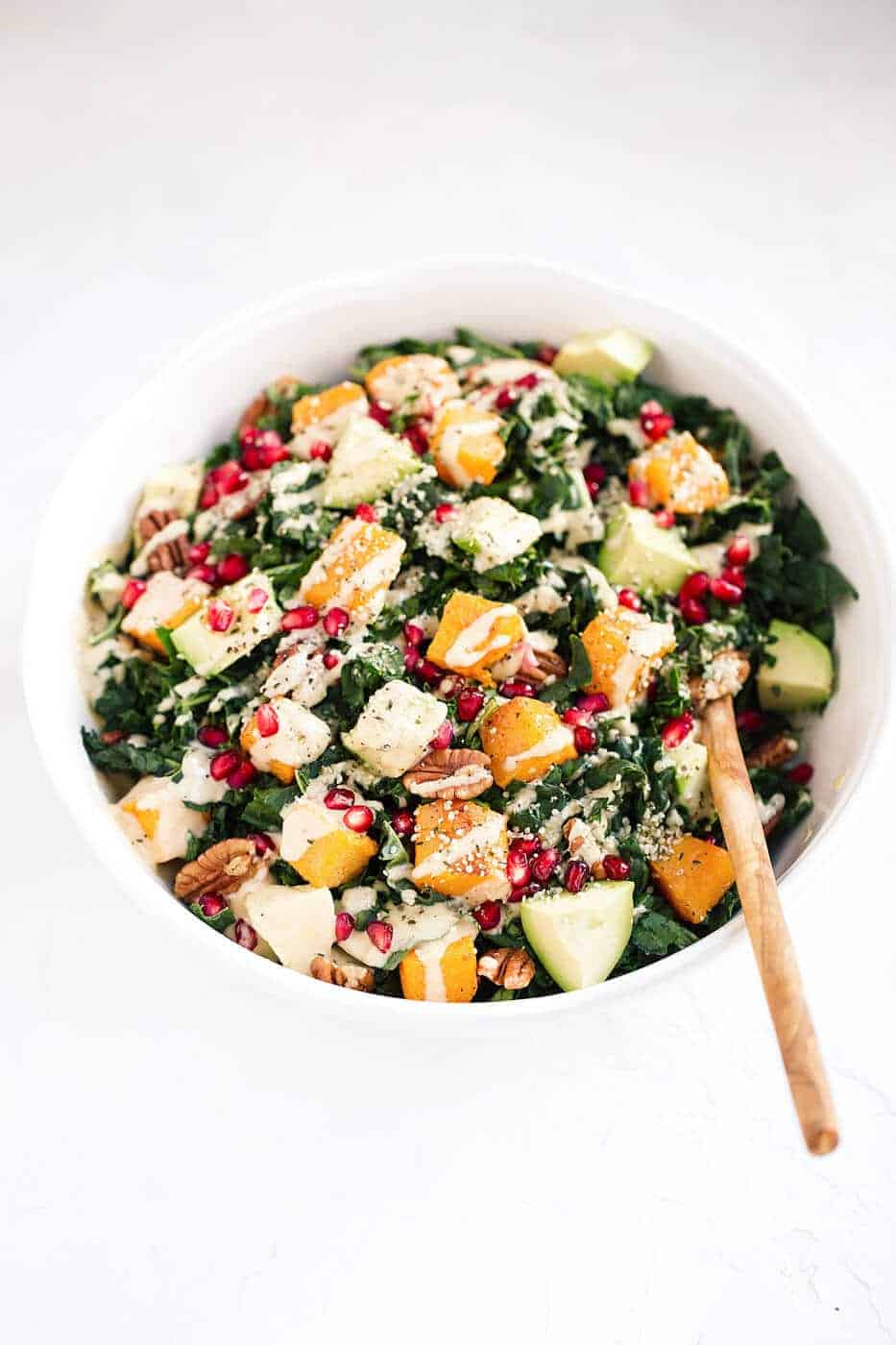 Roasted Butternut Squash Salad with Kale in a bowl with a wooden spoon