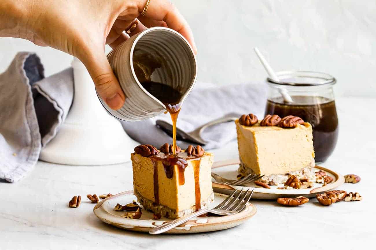 caramel sauce being poured on top of pumpkin cheesecake