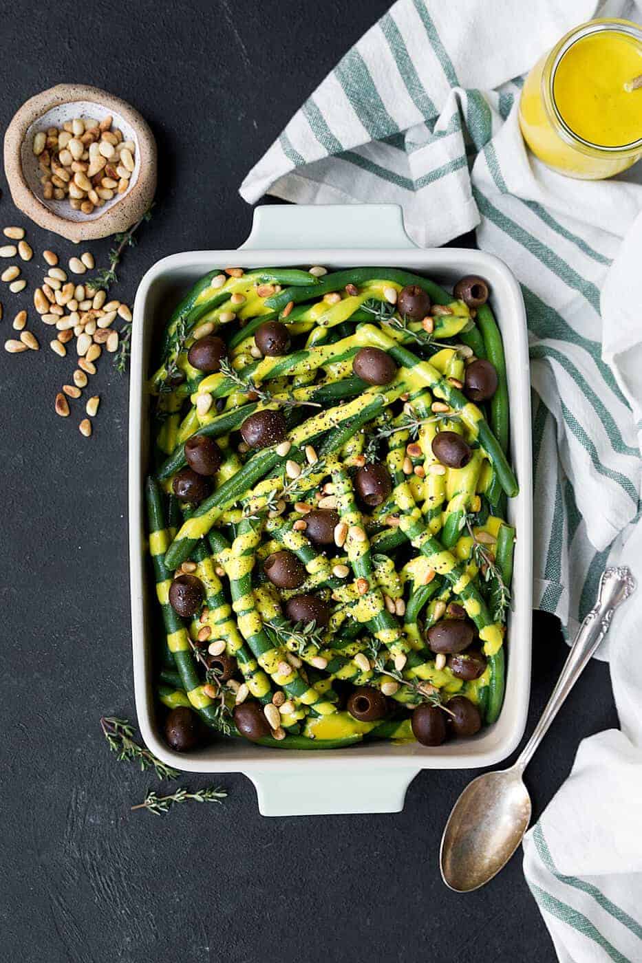Green beans in a serving dish with olives, pine nuts and pumpkin alfredo 
