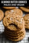a stack of almond butter cookies on a wire rack with flaked sea salt on top