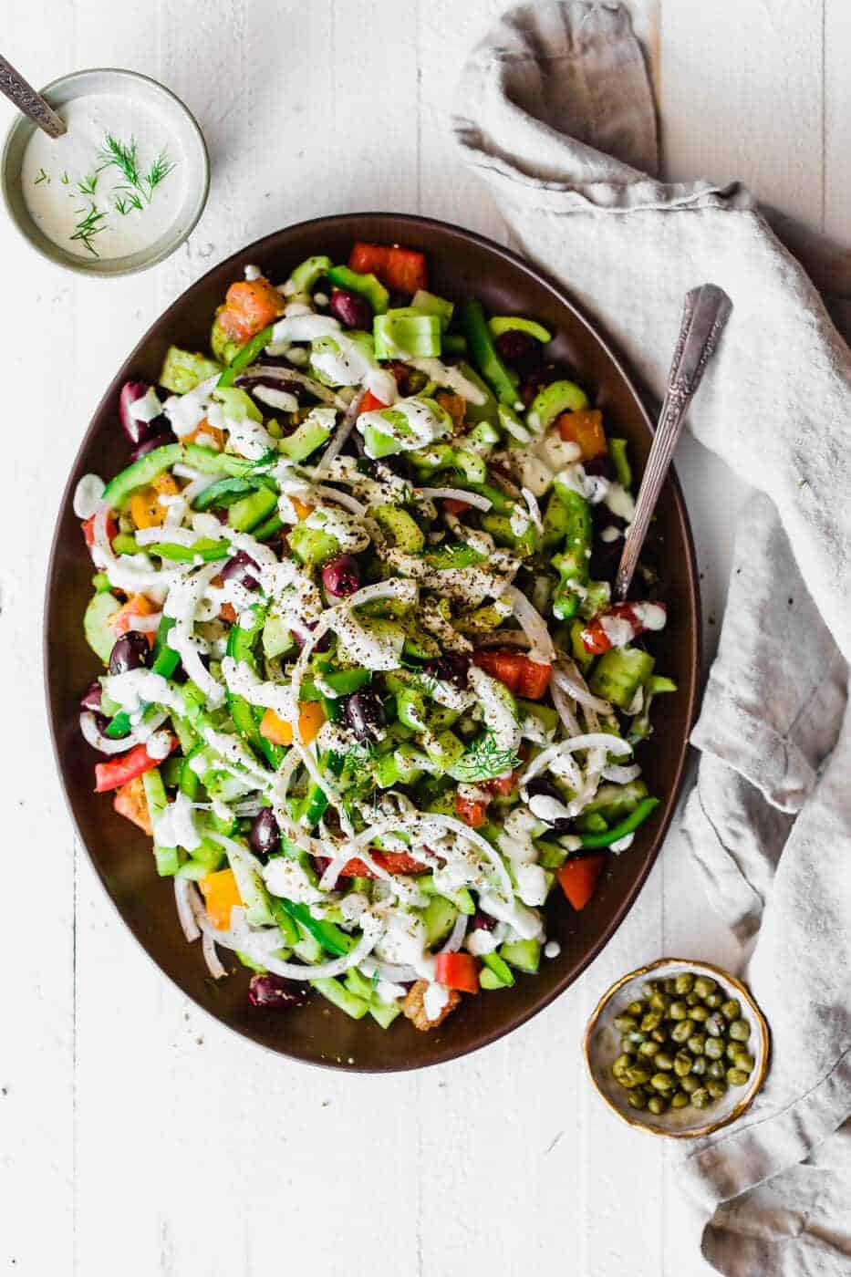 Paleo and Whole30 Greek Salad in a serving dish, drizzled with dill dressing