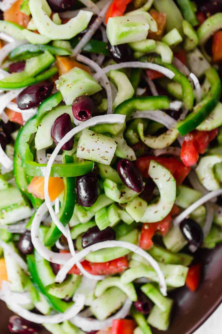 Diced cucumbers, olives, peppers and onions in a plate