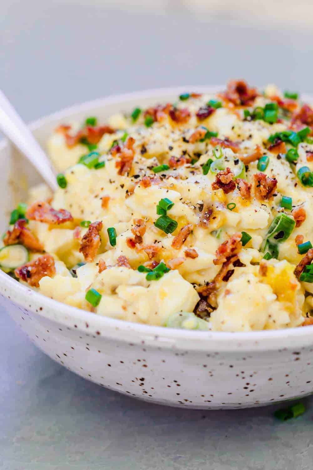 Egg salad with chopped bacon and green onions in a bowl