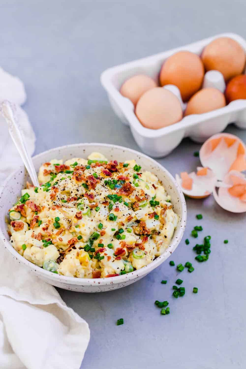 Egg salad in a bowl with six eggs in the background