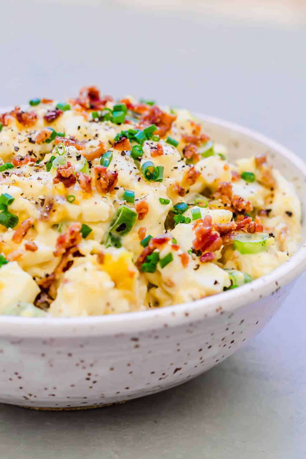 Egg salad garnished with green onions and crispy bacon