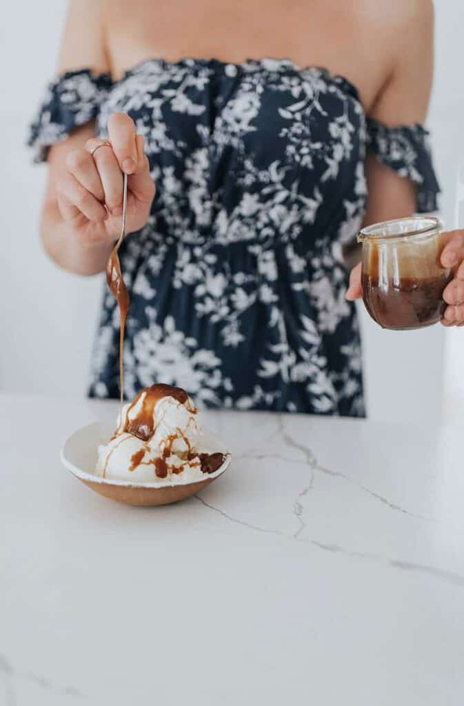 Woman drizzling caramel sauce onto to ice cream