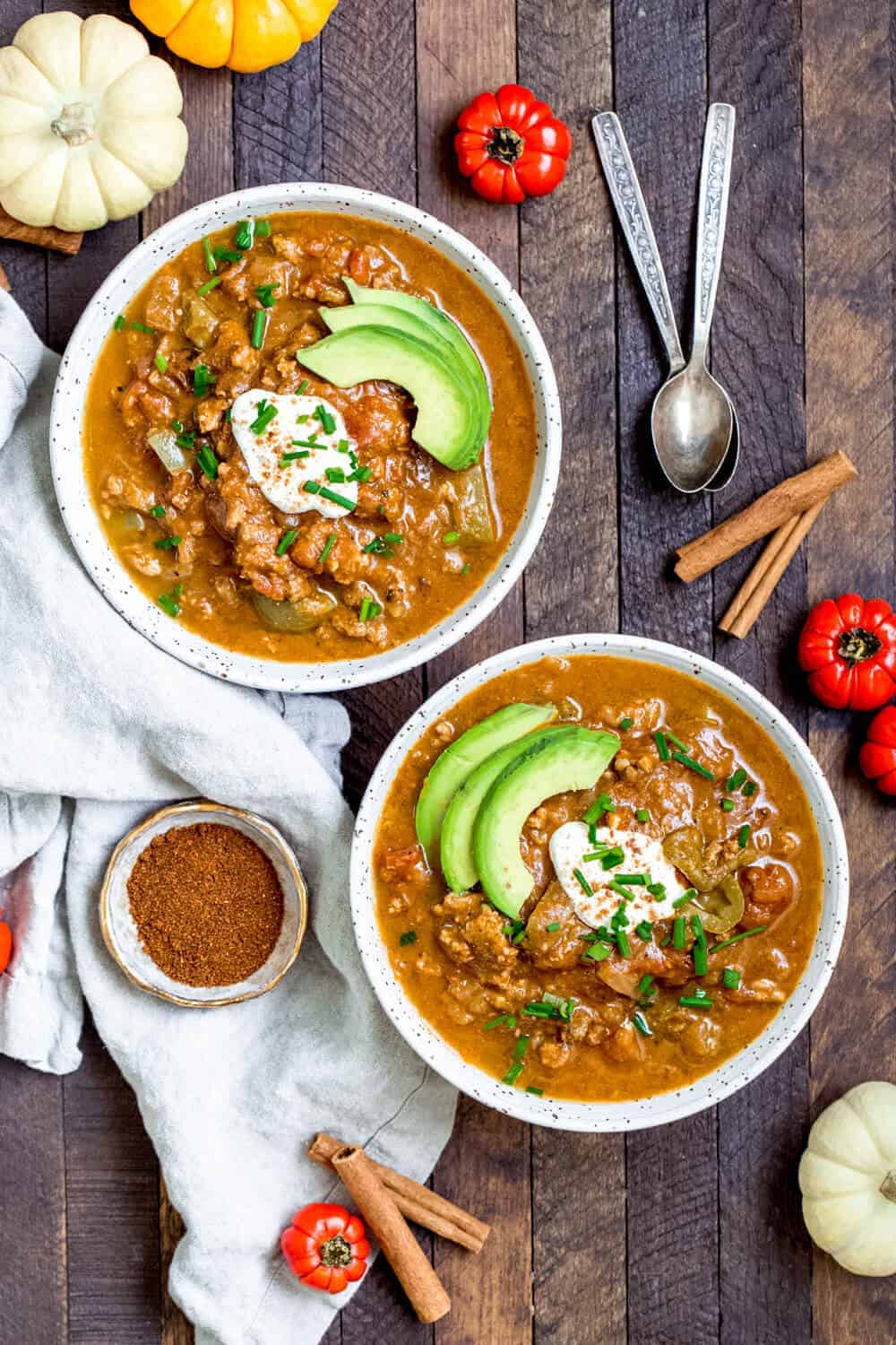 paleo pumpkin chili on a wooden table with tomatoes and spices