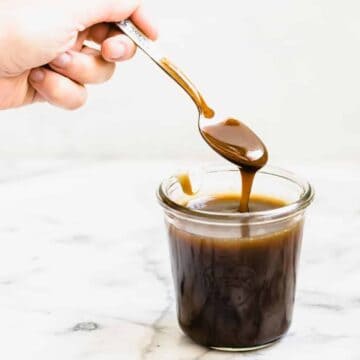 caramel sauce dripping into a glass jar with a spoon