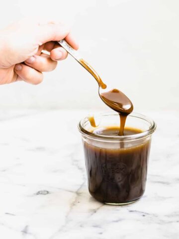 caramel sauce dripping into a glass jar with a spoon