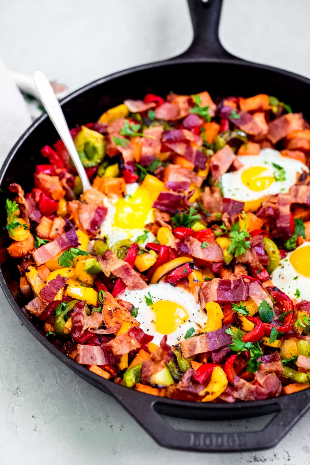 Sweet potato hash in a cast iron pan with a spoon