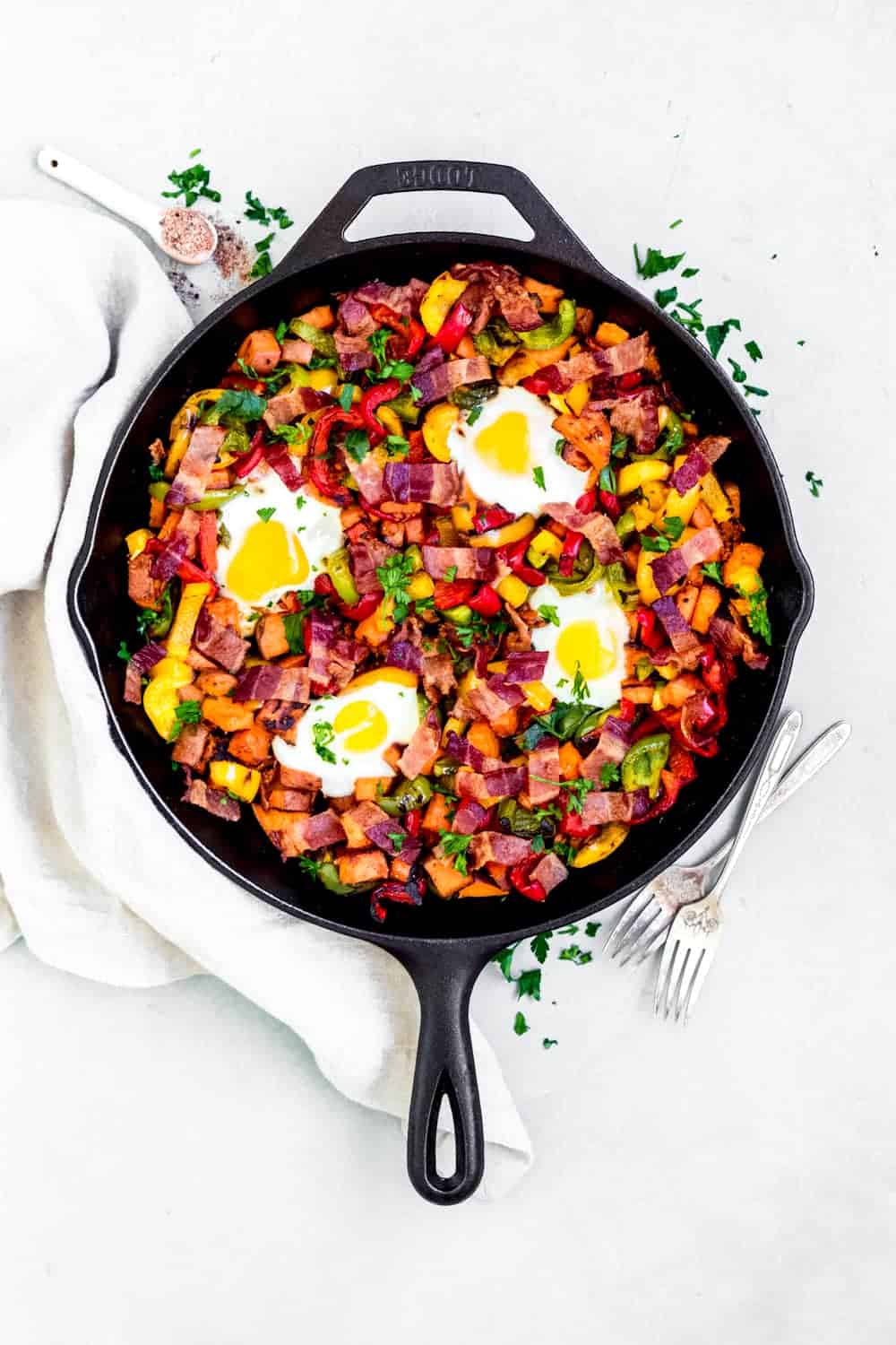 Sweet potato hash in a cast iron pan on a tea towel