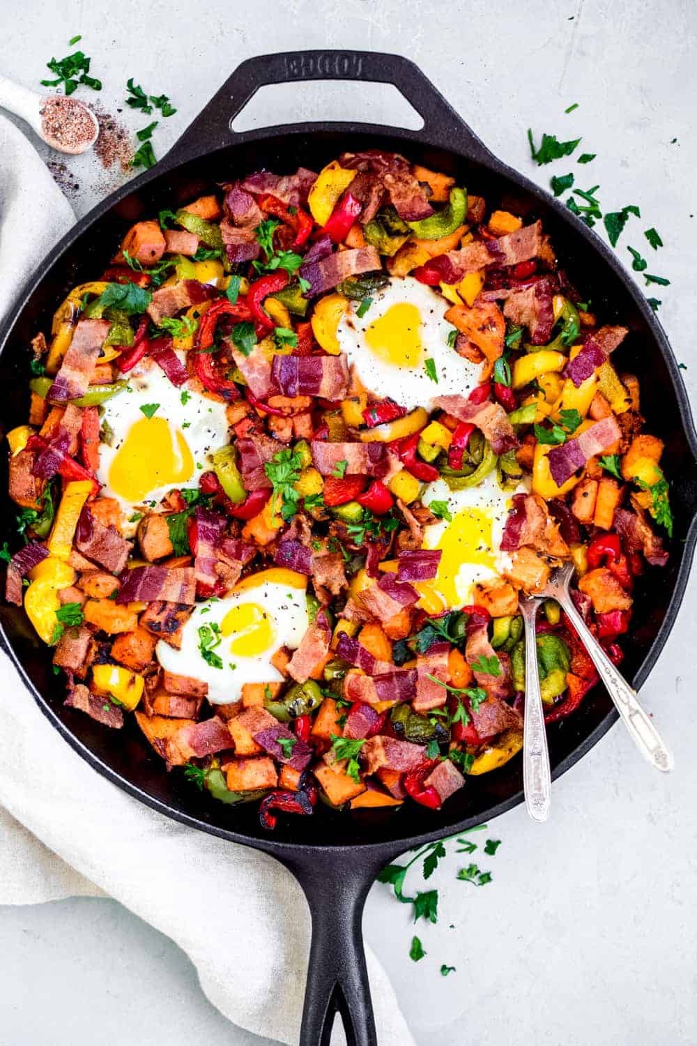 Sweet potato hash in a cast iron pan with forks, spices and herbs